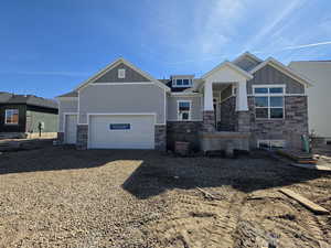 Craftsman-style house featuring stone siding, board and batten siding, driveway, and a garage