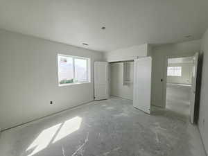Unfurnished bedroom featuring multiple windows and a closet