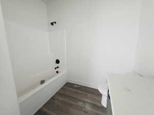 Full bath with dark wood-type flooring, vanity, and bathing tub / shower combination