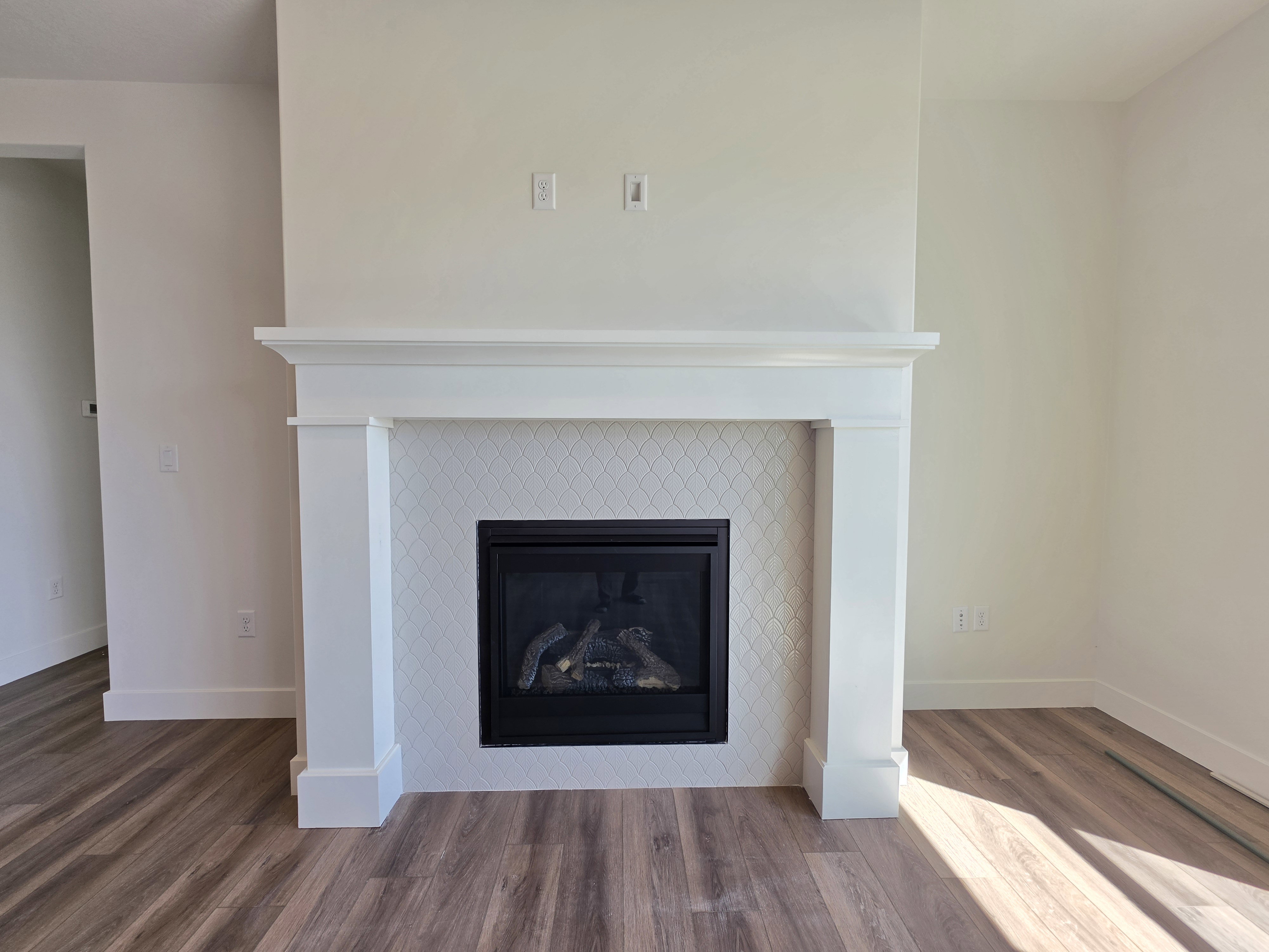 Fireplace featuring a white mantel, geometric tile surround, and a black insert