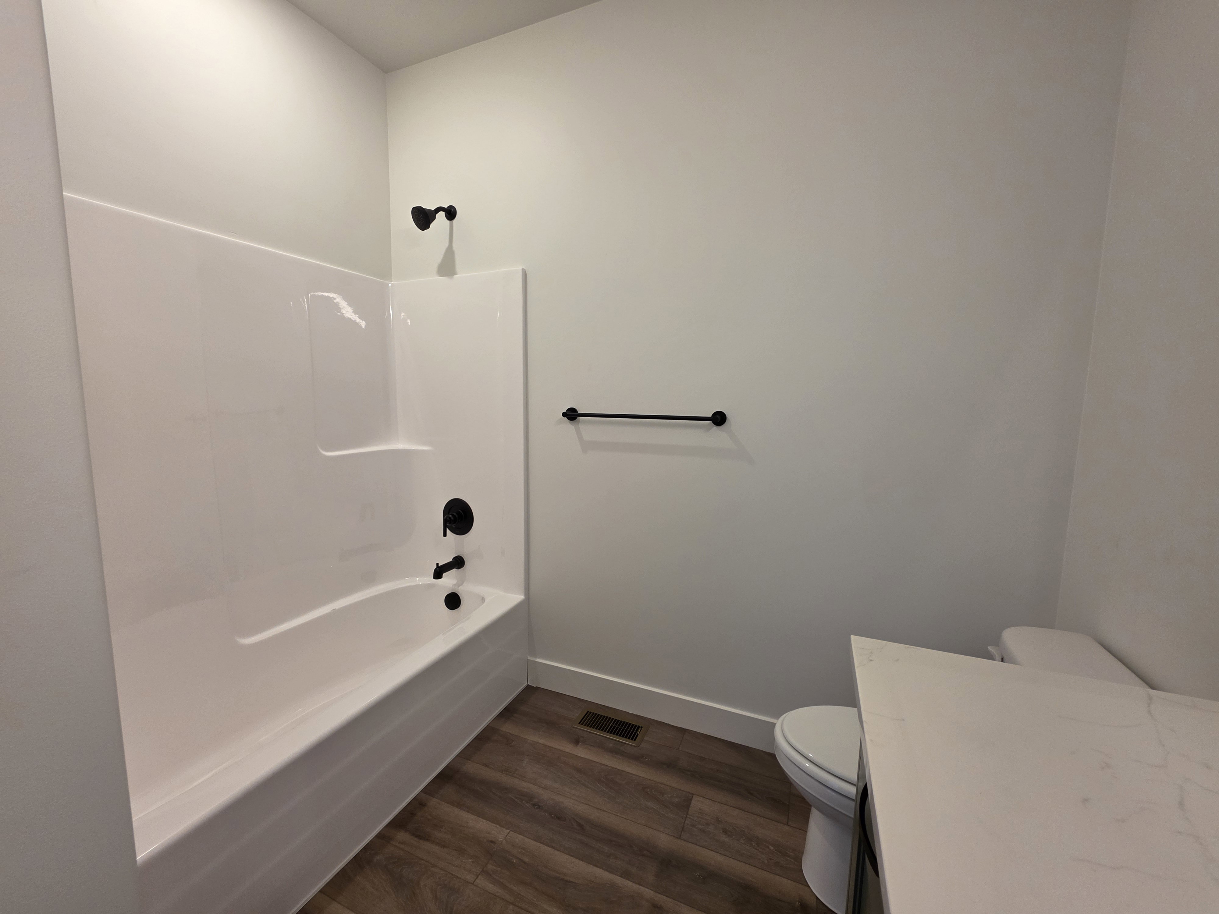 Bathroom featuring a white bathtub and shower surround with matte black fixtures