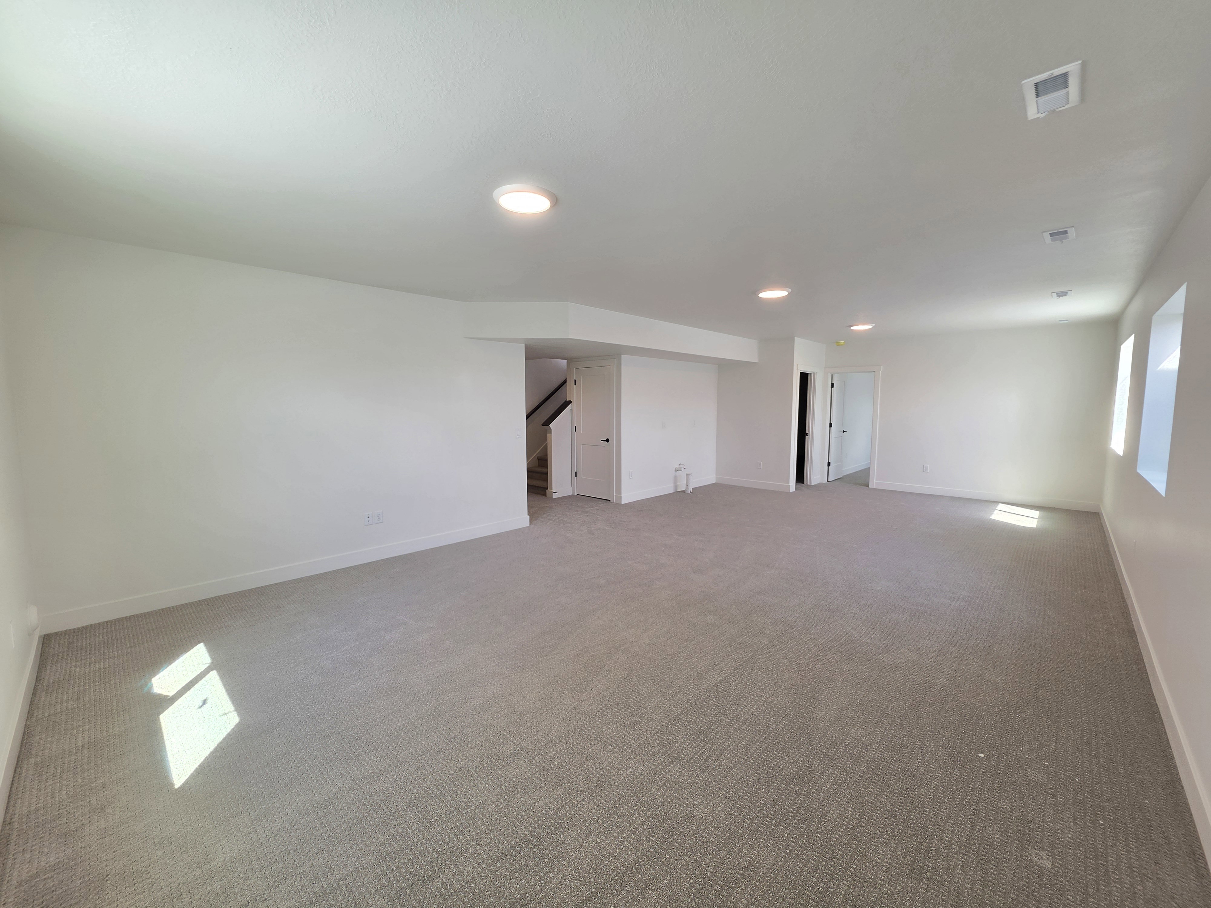Spacious carpeted room featuring recessed lighting, multiple windows, white baseboards, and a neutral color palette
