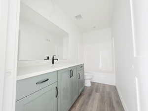 Full bathroom with vanity, dark wood-style floors, and shower / washtub combination