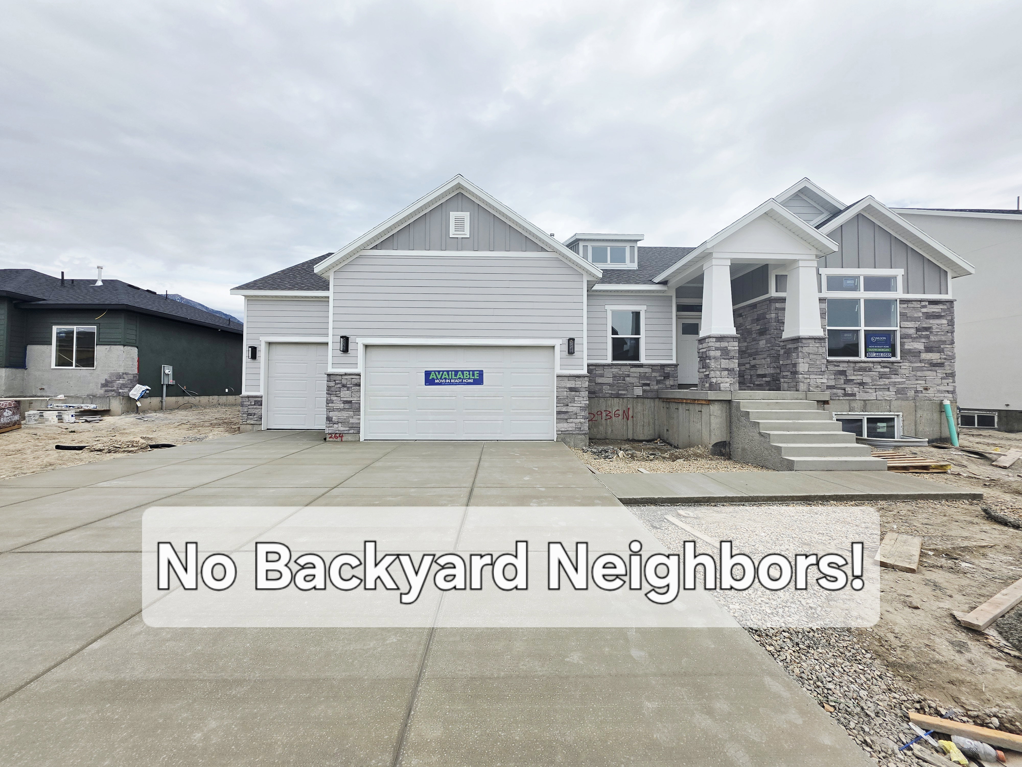 Light gray siding exterior with stone accents, a two-car garage, concrete driveway, and covered entry porch with white columns