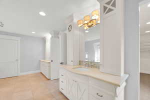 Bathroom with two vanities, recessed lighting, and a spacious closet