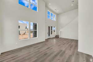 Unfurnished living room with a high ceiling, wood finished floors, and recessed lighting