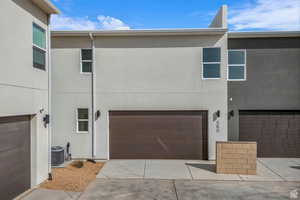 Back of property featuring stucco siding, a garage, and concrete driveway