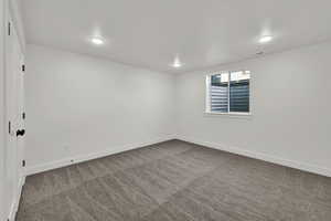 Empty room with dark colored carpet and baseboards