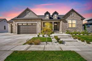 View of front of home featuring a garage, concrete driveway, brick siding, covered porch, and roof with shingles