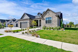View of front of property with a front yard, concrete driveway, a garage, and brick siding