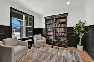 Sitting room with a decorative wall, wainscoting, recessed lighting, light wood finished floors, and ornamental molding
