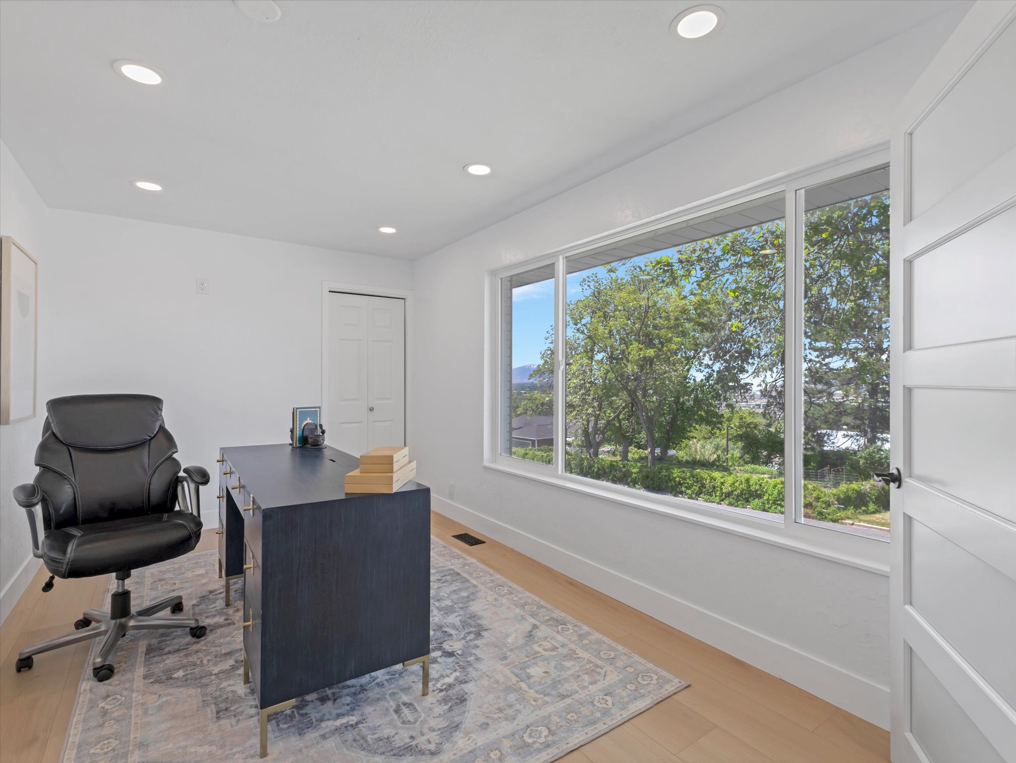 Room featuring expansive three-panel window, recessed lighting, light wood-finish flooring, and white trim