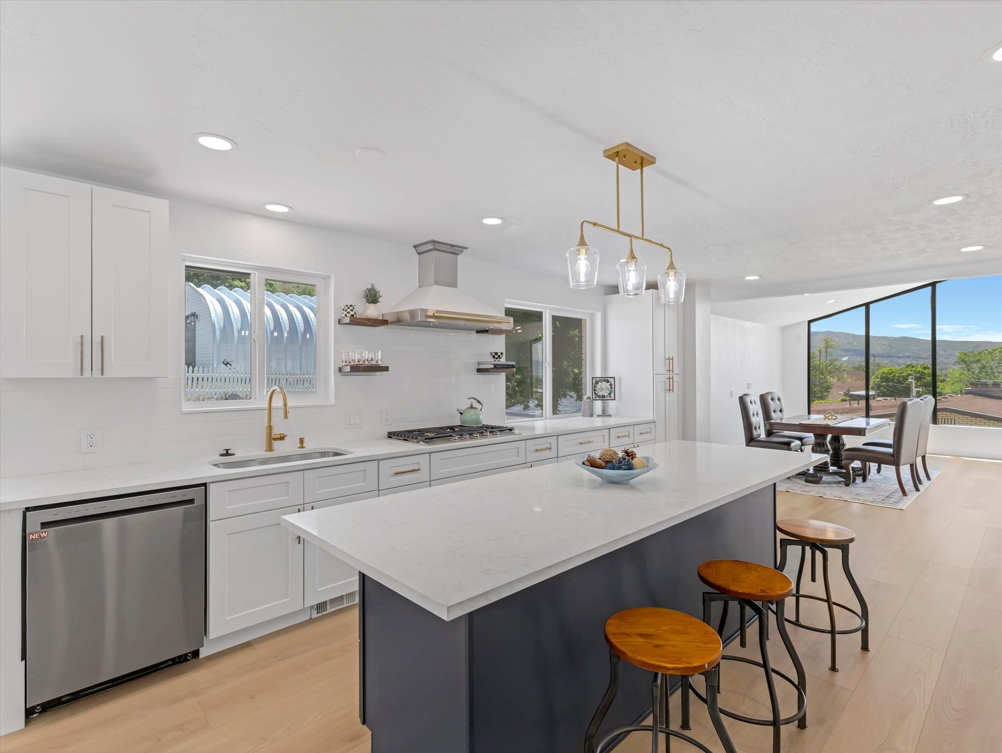 Modern kitchen featuring white cabinetry, light-toned wood-finish flooring, and a large center island with a contrasting base