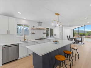 Modern kitchen featuring white cabinetry, light-toned wood-finish flooring, and a large center island with a contrasting base
