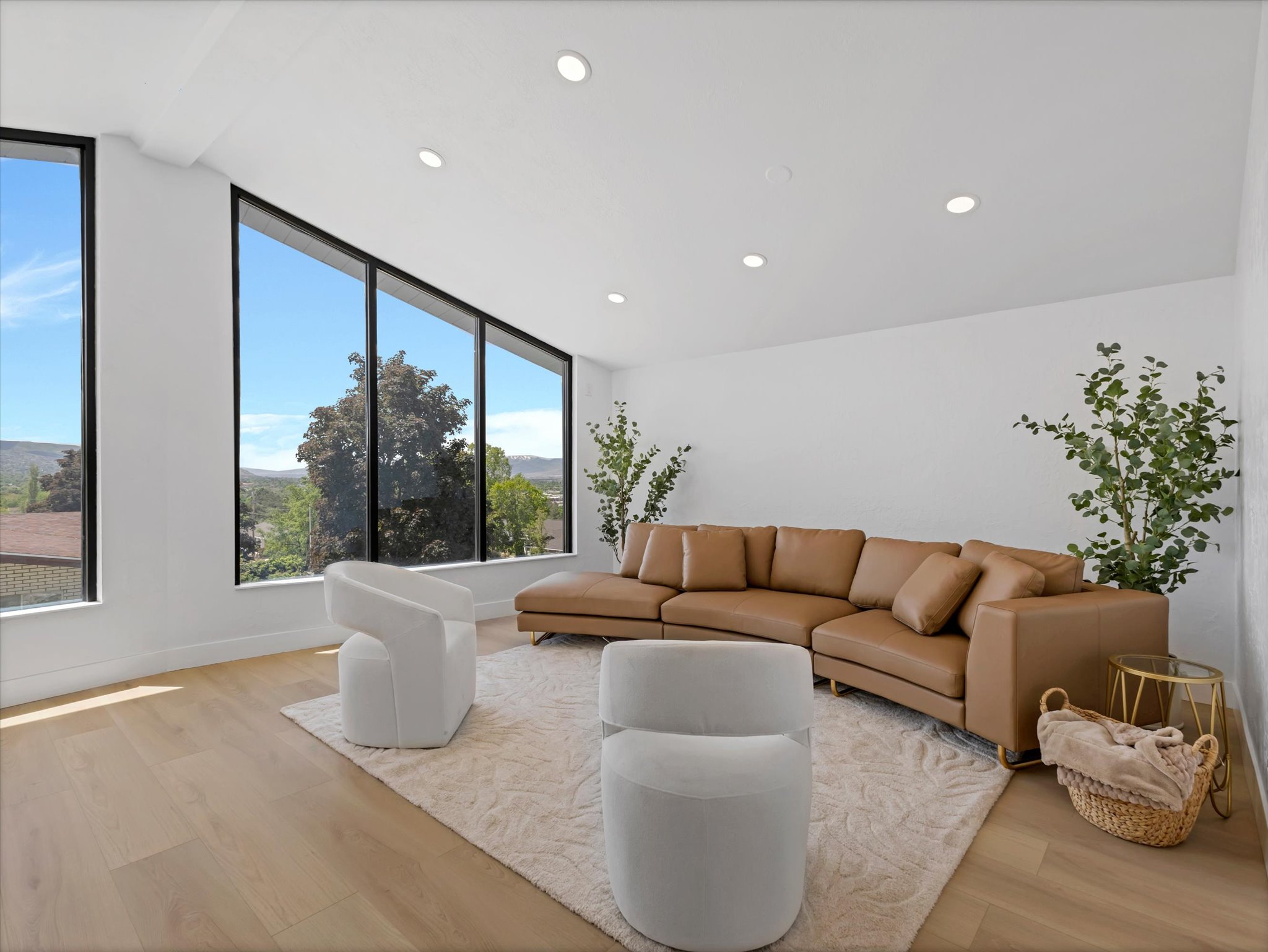 Expansive windows with black framing, wood-finish flooring, recessed ceiling lighting, and crisp white walls