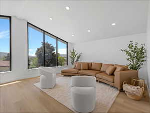 Expansive windows with black framing, wood-finish flooring, recessed ceiling lighting, and crisp white walls