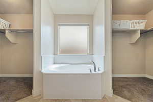 Full bath featuring light colored carpet, a spacious closet, and a garden tub