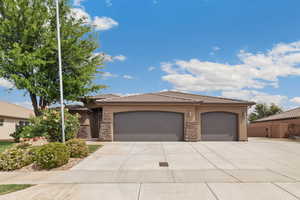 View of front of property with stucco siding, a tiled roof, stone siding, a garage, and driveway