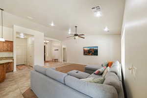 Living area with a ceiling fan, vaulted ceiling, light tile patterned floors, and suspended lighting