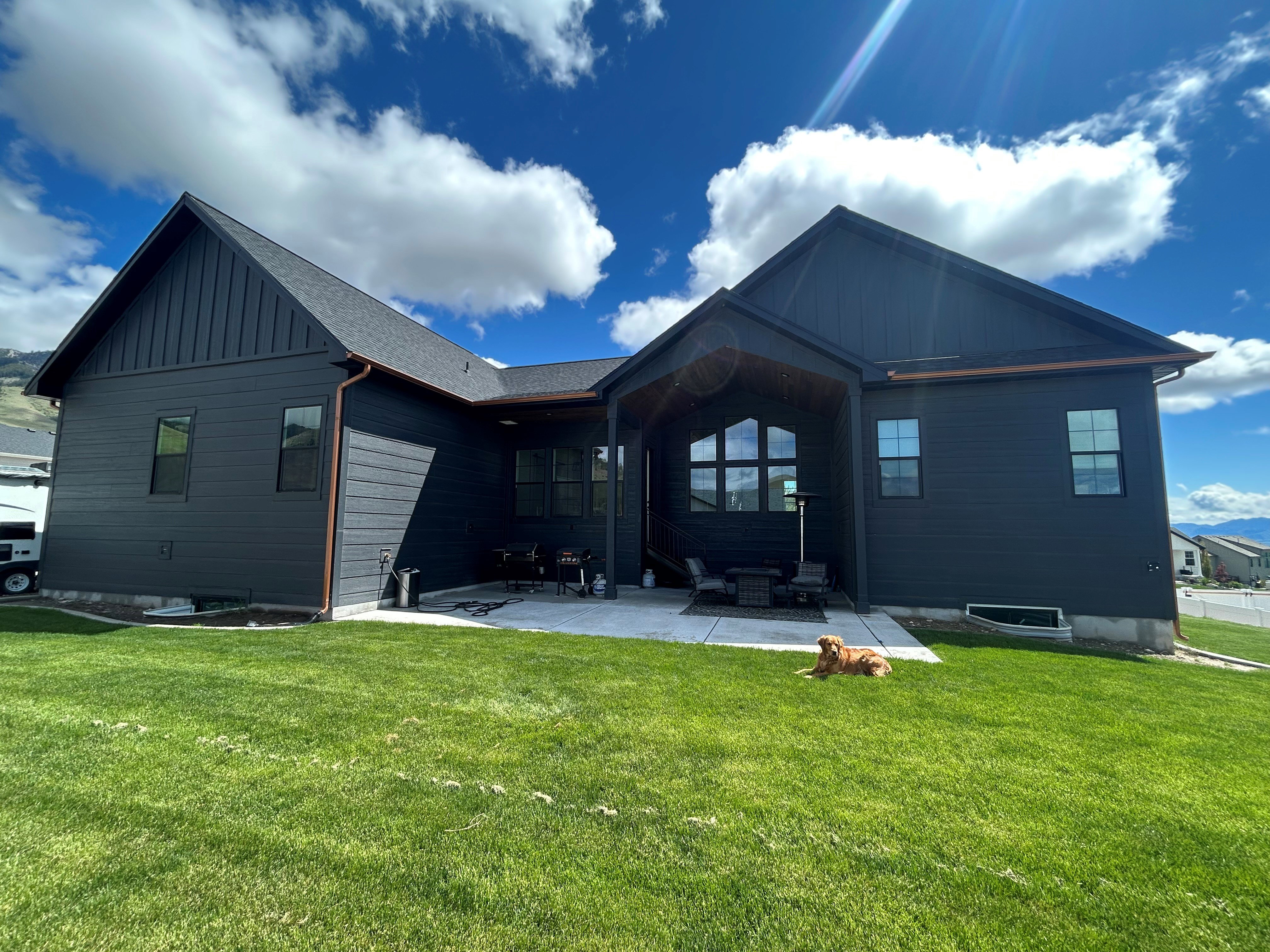Spacious backyard featuring a manicured lawn, an expansive concrete patio, and a covered patio area