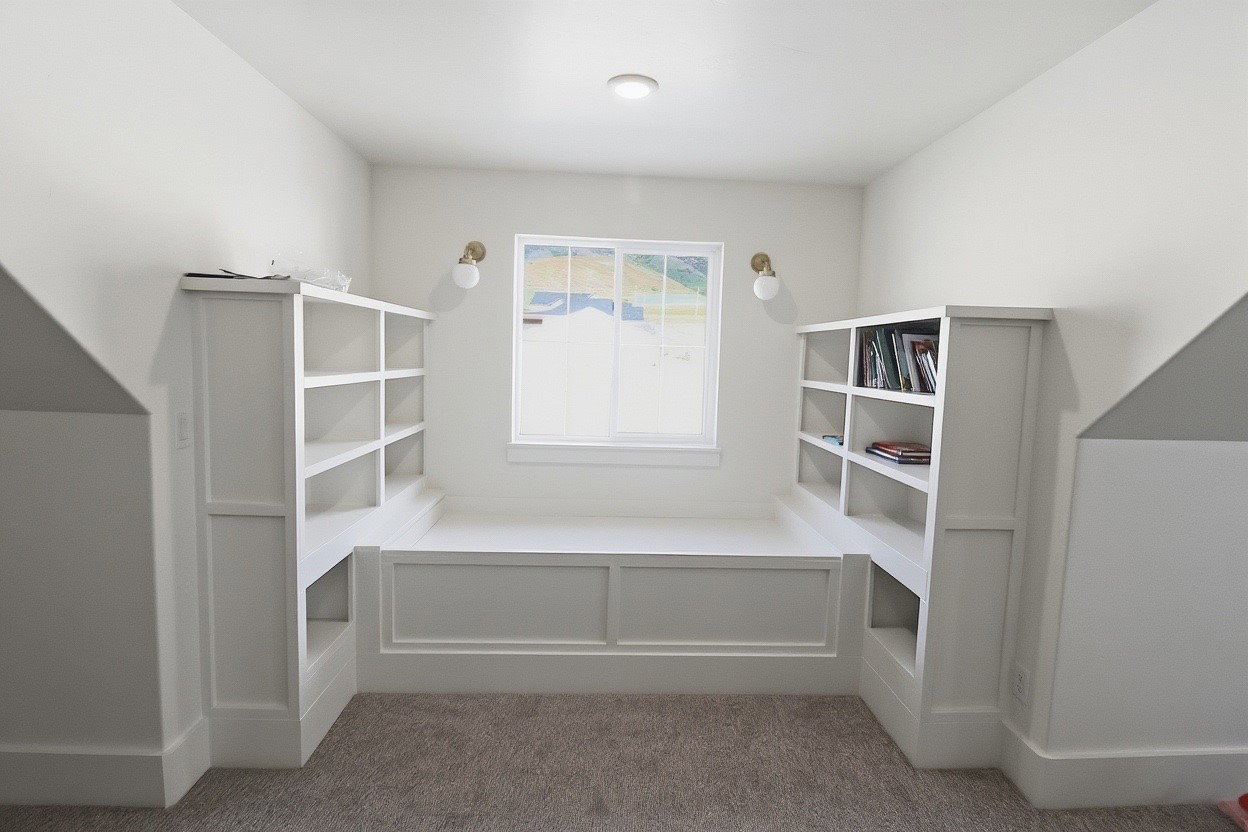 Built-in window seat with integrated shelving, white trim, and wall-mounted sconces
