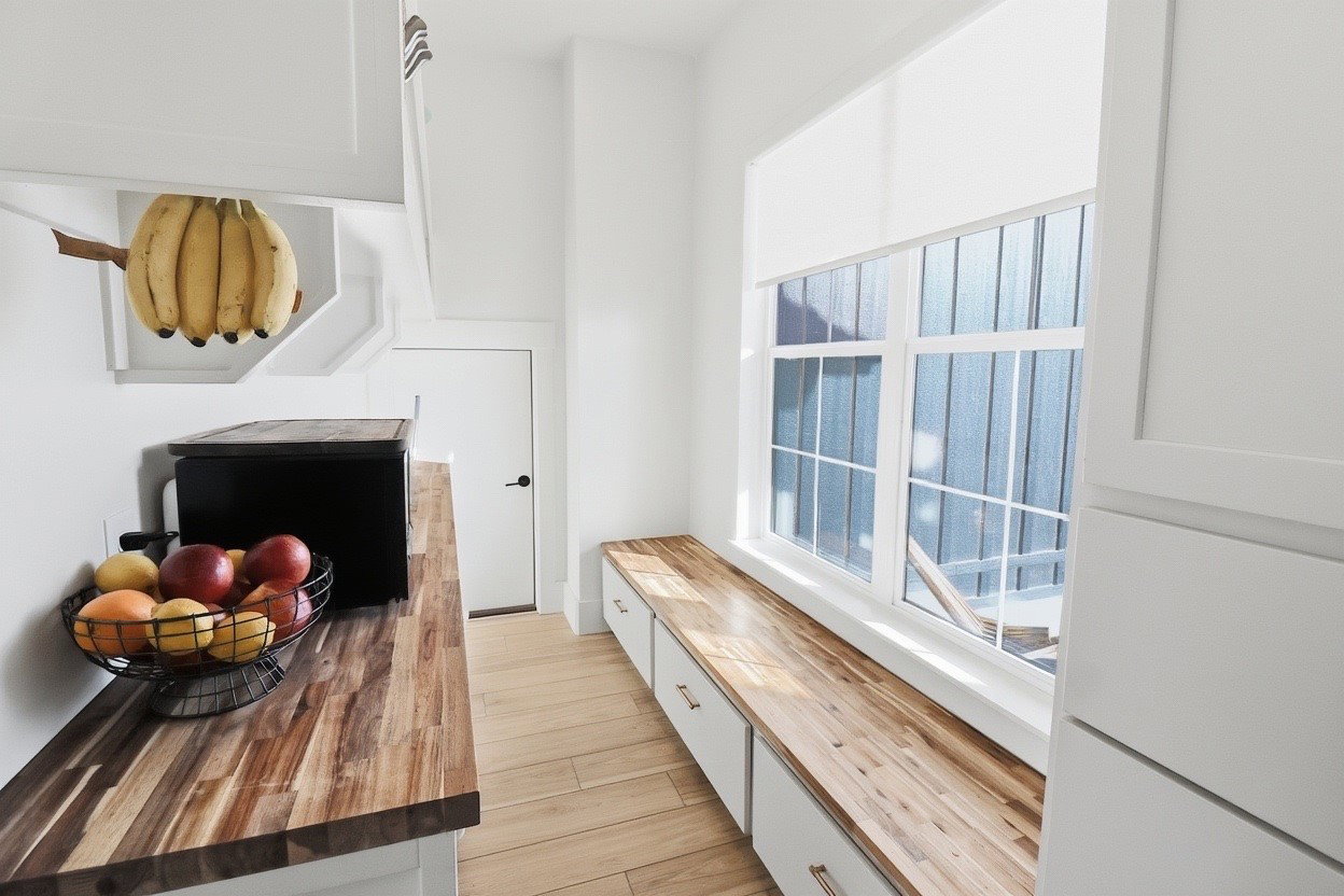 Bright interior space featuring a window bench with integrated storage and a natural wood-finish countertop