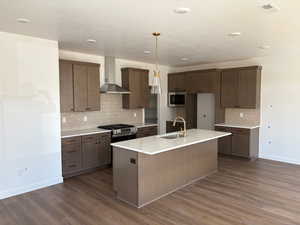 Kitchen with tasteful backsplash, an island with sink, and dark wood-style floors