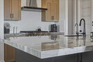 Kitchen featuring light stone countertops, decorative backsplash, and stainless steel range with gas stovetop