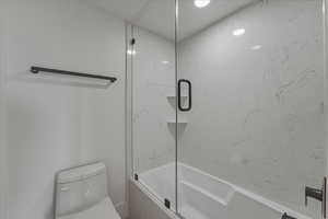 Full bathroom with toilet and enclosed tub / shower combo