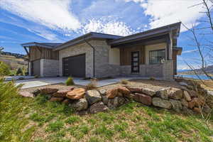 Contemporary home featuring board and batten siding, stone siding, an attached garage, and concrete driveway