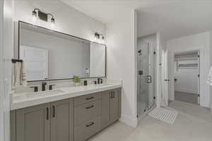 Full bath featuring double vanity, a stall shower, a spacious closet, and light tile patterned floors