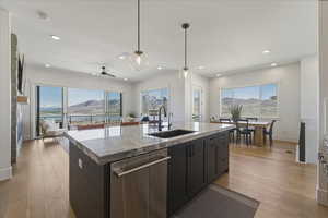Kitchen with a mountain view, dishwasher, an island with sink, light wood-style floors, and decorative light fixtures