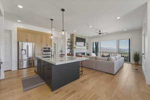 Kitchen with two tone cabinetry, light wood-style flooring, a breakfast bar area, stainless steel appliances, and an island with sink