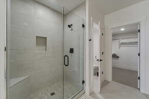 Full bathroom with a spacious closet, a stall shower, and light tile patterned floors