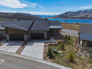 View of front of home featuring driveway, an attached garage, a chimney, and a water and mountain view