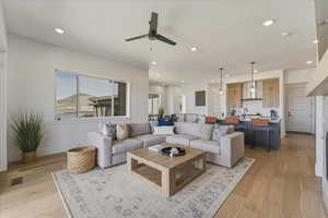 Living area with a ceiling fan, light wood-style flooring, and recessed lighting