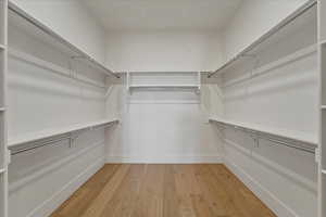 Walk in closet with light wood-style floors