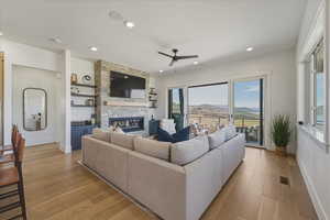 Living room with light wood-type flooring, a fireplace, ceiling fan, and recessed lighting