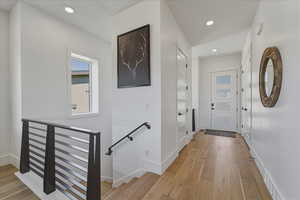 Corridor featuring light wood-style floors, an upstairs landing, and recessed lighting