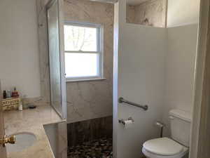 Full bathroom featuring a marble finish shower and vanity
