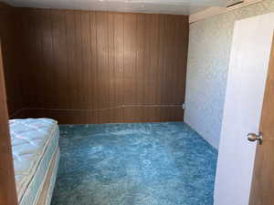 Unfurnished bedroom with carpet and wooden walls