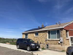 View of home's exterior featuring brick siding, roof mounted solar panels, and a shingled roof