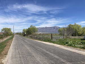 View of asphalt road with a mountain view, a view of rural / pastoral area, and traffic signs