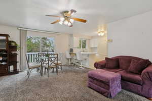 Living room featuring light colored carpet, a ceiling fan, and a textured ceiling