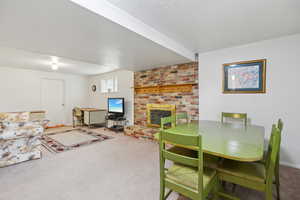 Carpeted dining area with a brick fireplace and a textured ceiling