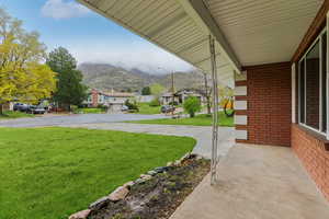 View of green lawn with a mountain view, a residential view, and a porch