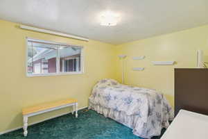 Bedroom with dark colored carpet and a textured ceiling