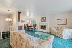 Living room featuring dark colored carpet, suspended lighting, and a textured ceiling