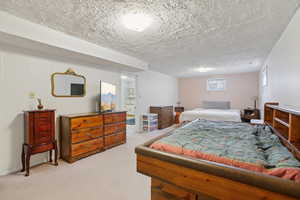 Bedroom featuring light carpet, a textured ceiling, and wooden walls