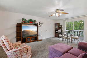 Living area featuring a ceiling fan, carpet flooring, and a textured ceiling